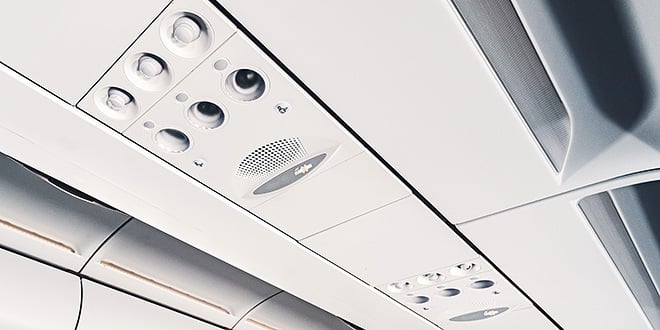 Close-up of an aircraft cabin ceiling panel showing passenger service units with air vents, reading lights, and speaker, emphasising precision interior design.
