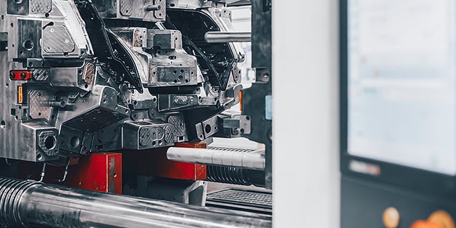 Close-up of a large automotive injection mould inside a production machine, showing metallic surfaces and precision cavities that ensure flawless part formation.