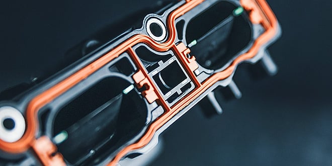 Close-up of a multi-component plastic automotive part with integrated red sealing elements, designed for a perfect fit and durable assembly.