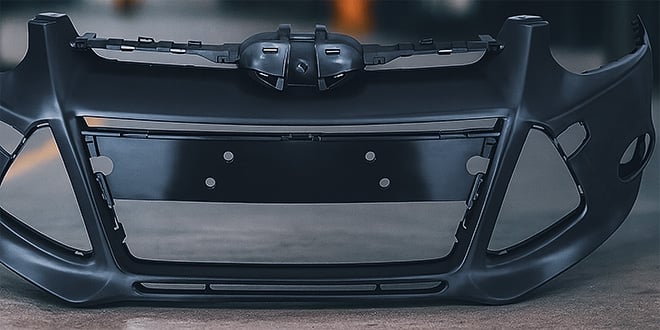 Front view of a black plastic car bumper showing smooth contours and consistent surface quality, demonstrating strength and precision in automotive moulding.