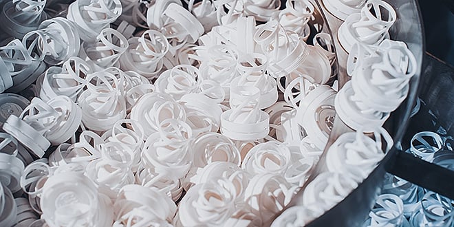 Large bin filled with numerous white plastic sealing components, demonstrating mass production capability and consistent quality of packaging parts.