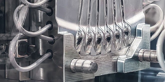 Close-up of a shiny multi-cavity injection mould with cooling channels and nozzles, emphasising reliable and precise plastic part production.