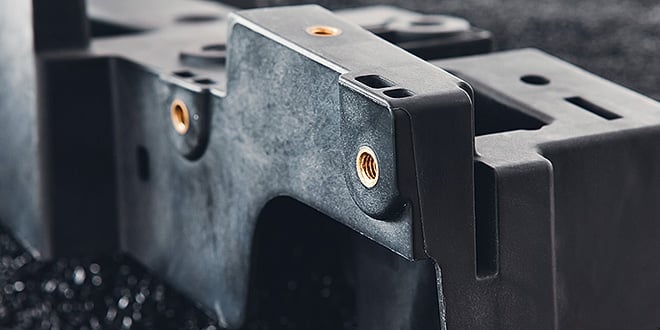 Detailed view of a moulded plastic component with integrated metal inserts, showcasing encapsulation technology for electronics manufacturing.