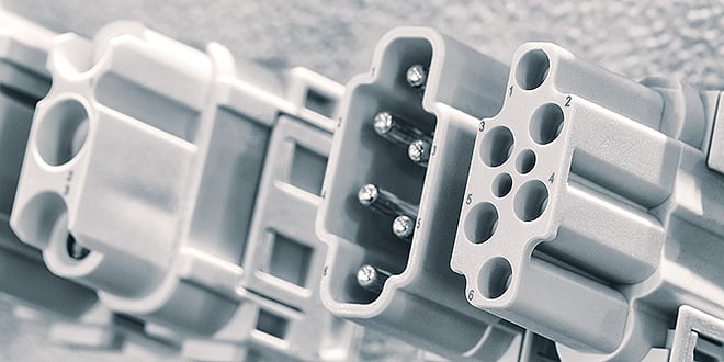 Row of light grey plastic electrical connectors with visible metal pins, demonstrating precision engineering and consistent part geometry for semiconductor applications.