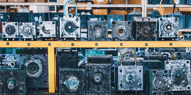 Various metal injection moulds arranged on storage shelves in a workshop, illustrating organised tool maintenance and protection practices in mould manufacturing.