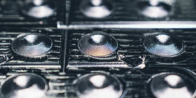 Close-up of precision plastic optical lenses with reflective surfaces.