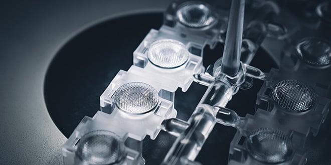 Transparent plastic optical components connected by runners after molding, featuring clear lens structures that demonstrate high see-through quality and surface precision.