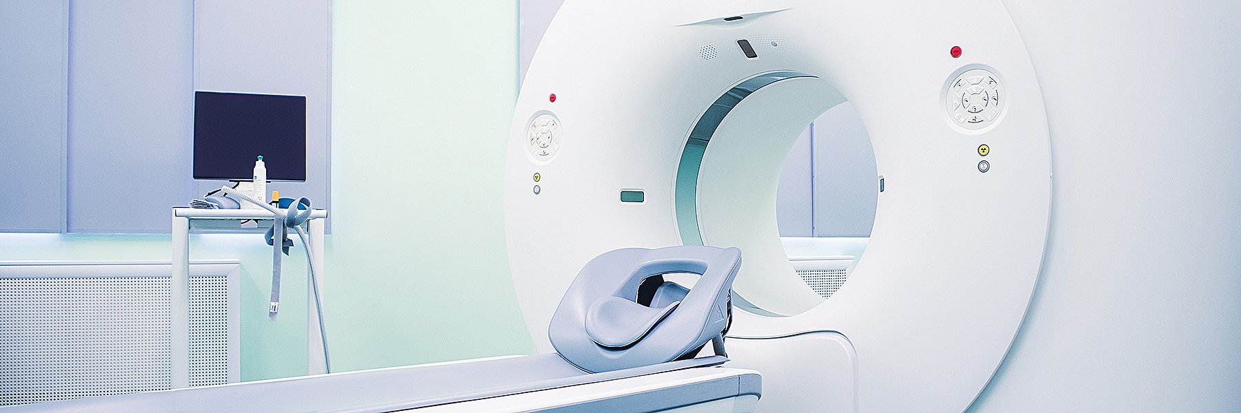 An examination room features a close-up view of a CT scanner.