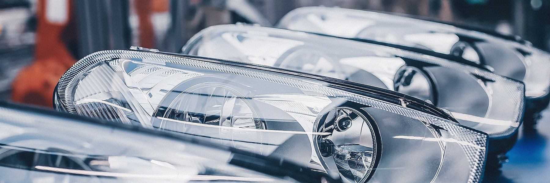 A close-up view captures vehicle headlights poised for assembly on a production line.