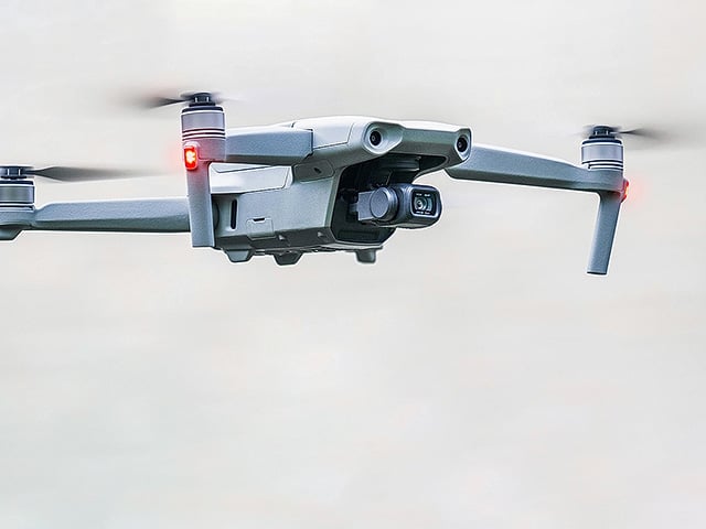 A surveillance drone soars gracefully through a clear, cloudless sky.