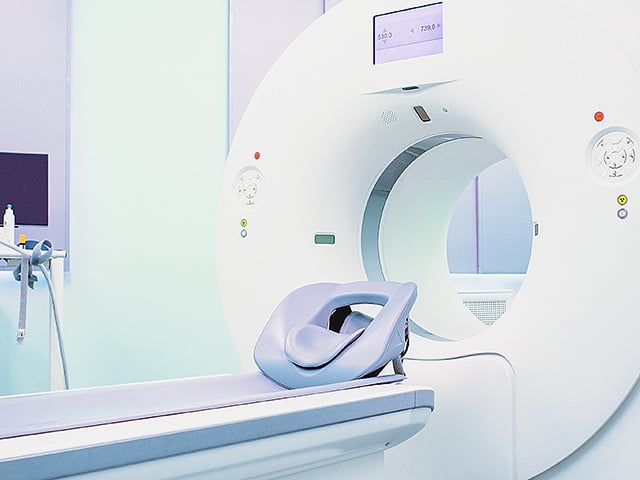 An examination room features a close-up view of a CT scanner.