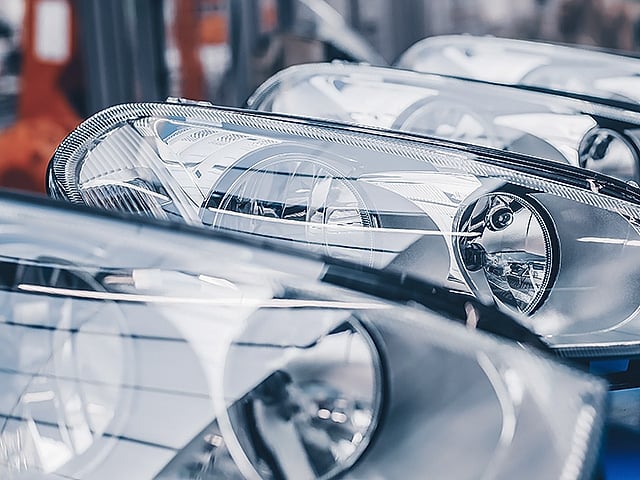 A close-up view captures vehicle headlights poised for assembly on a production line.